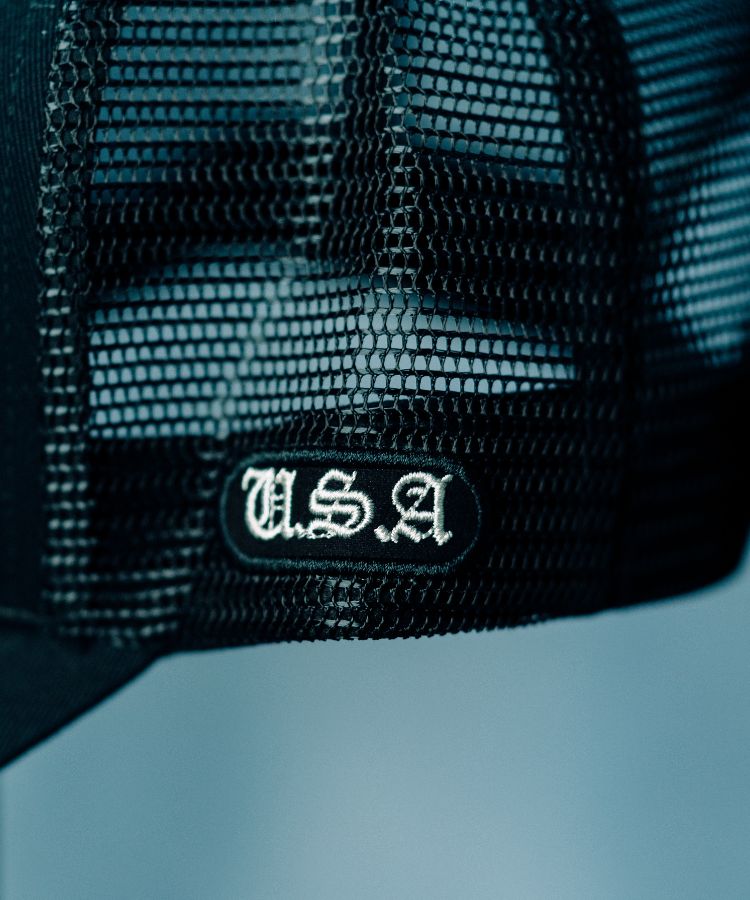 Close-up of the Black PK Cap with 'USA' embroidery by Philip Karto on a light blue background