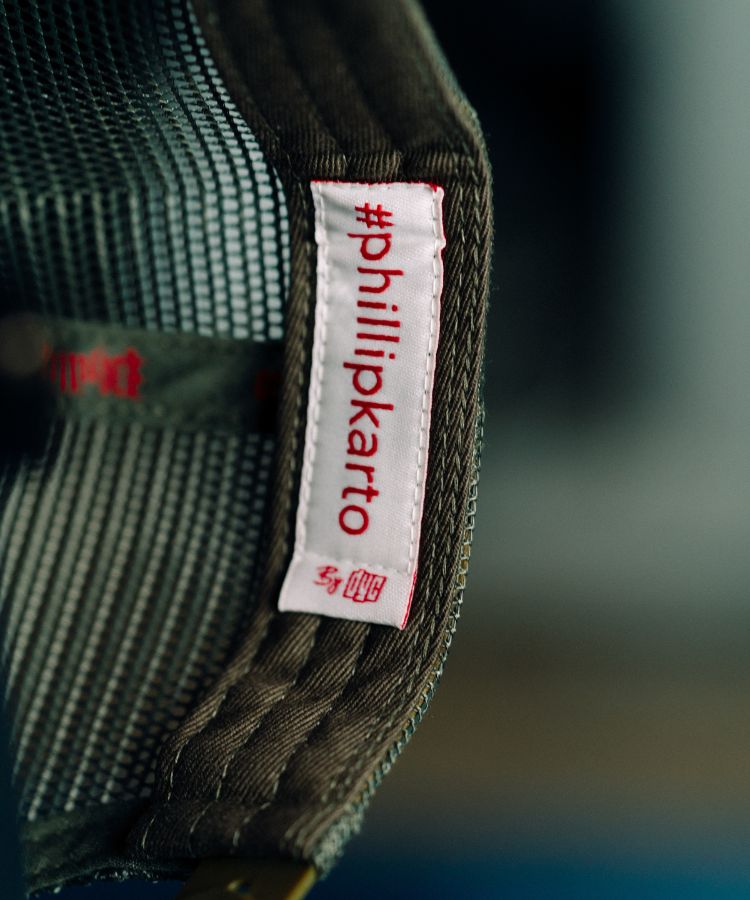 Close-up of a '#phillipkarto' label on Camouflage PK Cap "Not For Everyone" Model