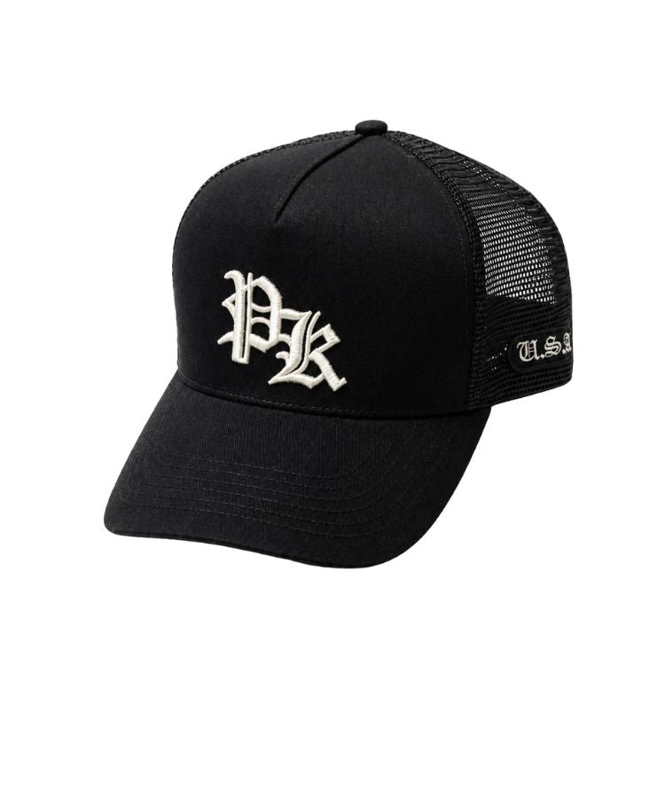 A black trucker-style baseball cap with a curved brim, black mesh back panels, and white embroidered lettering on the front and side. The front features a stylized 'PK' monogram, by Philip Karto