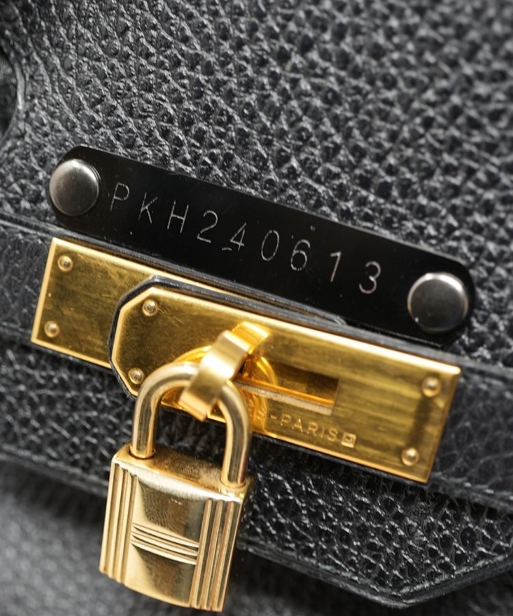 Close-up of a black leather bag with a gold lock and visible brand name.