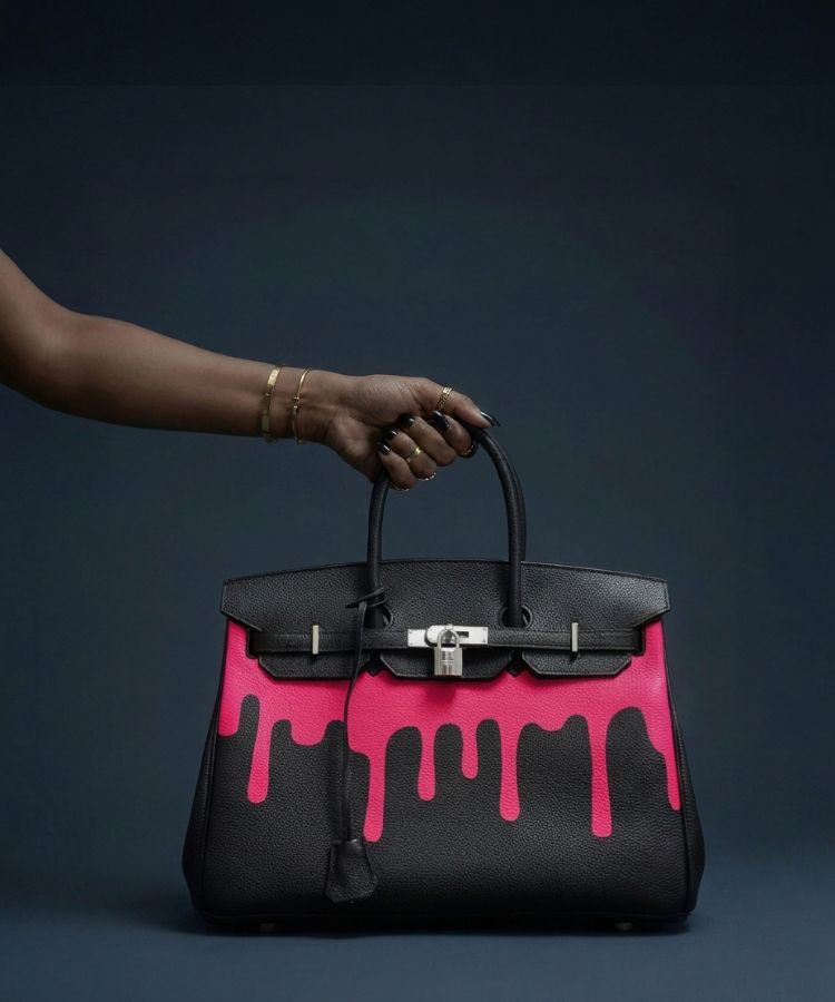Black vintage Hermès Birkin handbag with pink dripping design by Philip Karto, model Art Is Freedom, held by a hand against a dark background