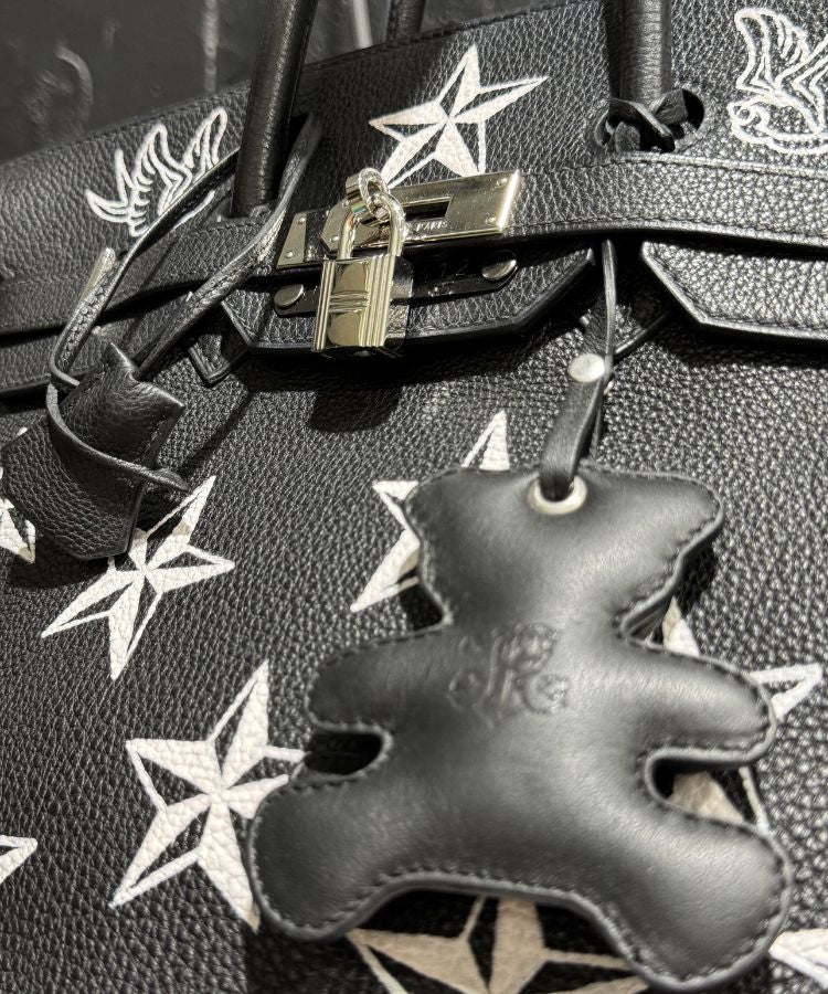Black leather keychain on Philip Karto handbag with star designs on the textured surface of vintage Hermès Birkin blacl bag