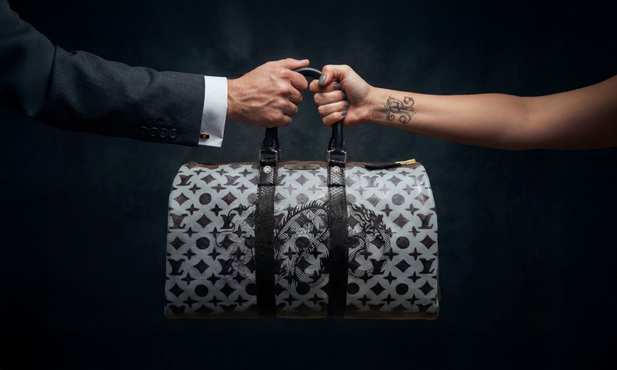 Philip Karto Black Dragon LV Speedy held by two hands, the left hand is a man hand and the right hand is a woman hand with a black tattoo on the wrist, on a black background, horizontal image for desktop view