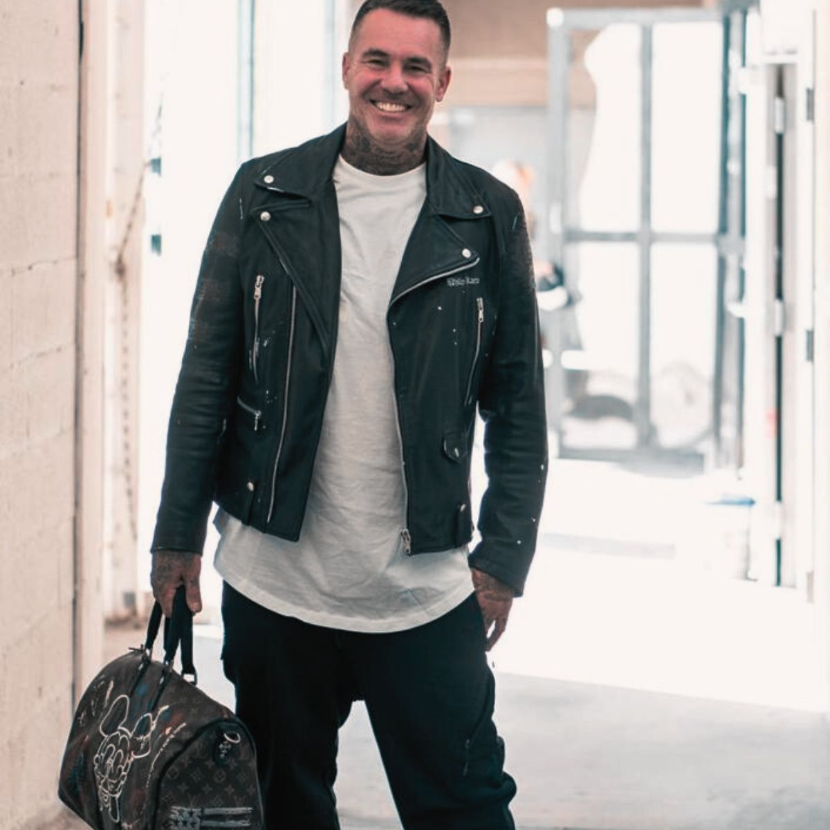 Artist Philip Karto in fromt of The Philip KArto Atelier holding one of his creations on a Louis Vuitton Keepall bag.