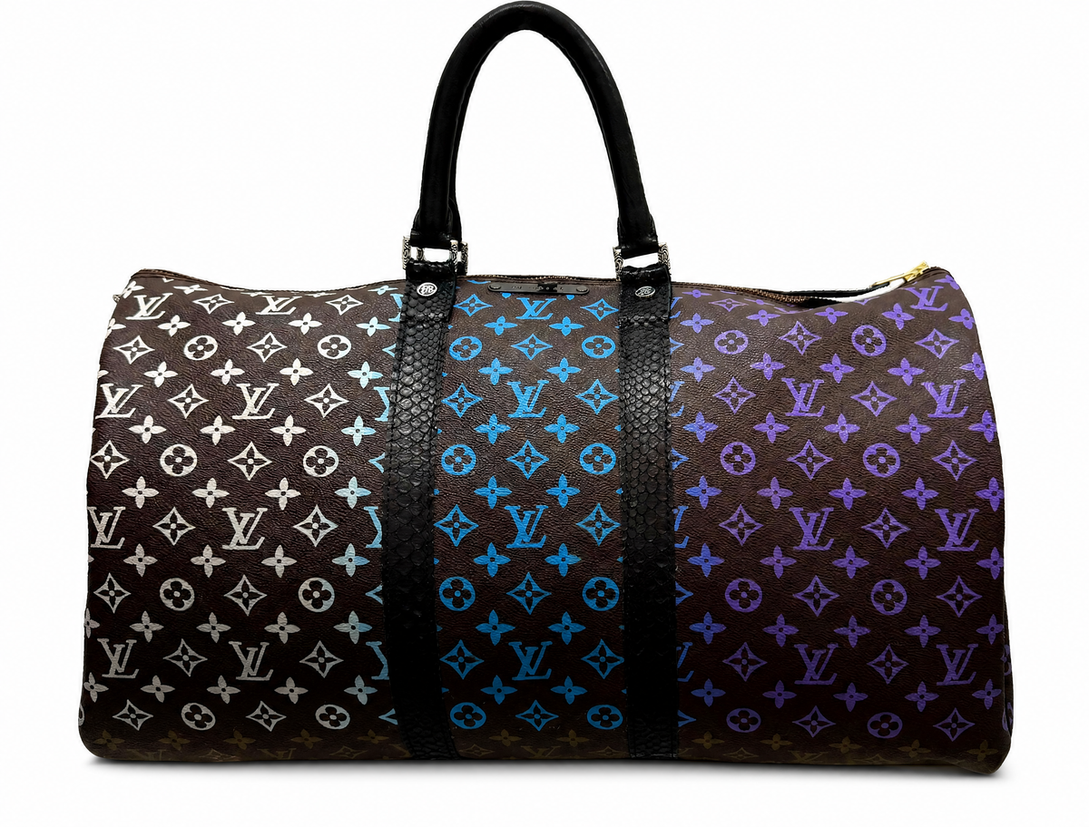 A Louis Vuitton monogram duffle bag featuring a tri-color gradient monogram pattern transitioning from white to blue to purple on a dark brown background, with black leather handles and trim.
