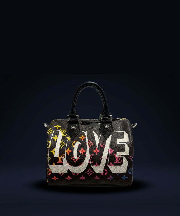 A Louis Vuitton handbag with a black monogram pattern and the word 'LOVE' printed across the front in large white letters, set against a dark navy background.