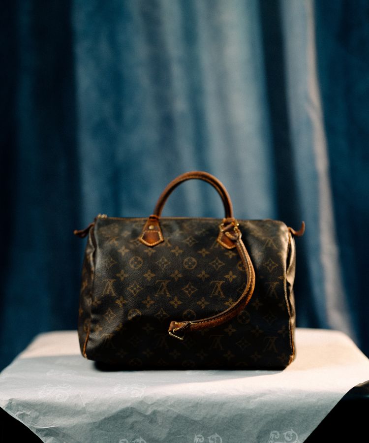 Brown leather handbag with visible brand logo on a blue fabric background