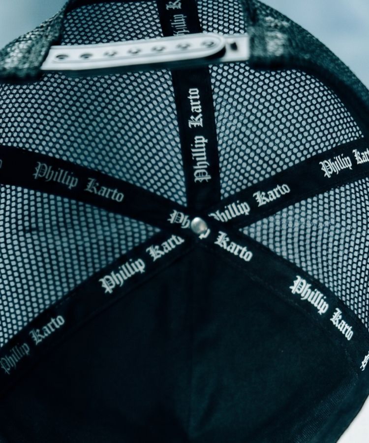 Insid of a black cap with 'Phillip Karto' branding on a textured background