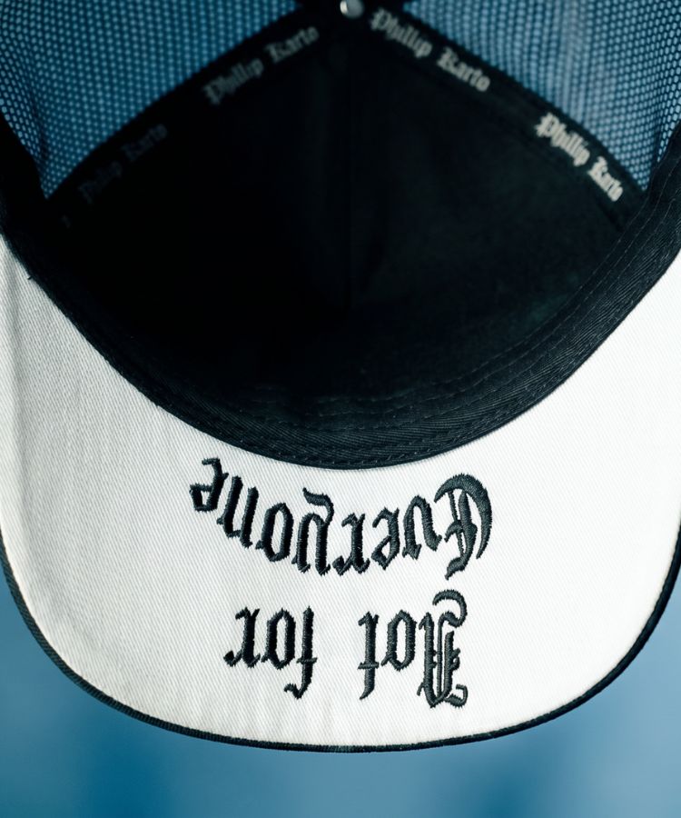 Close-up of a Philip Karto Black cap with Not For Everyone text on the visor on a blue background