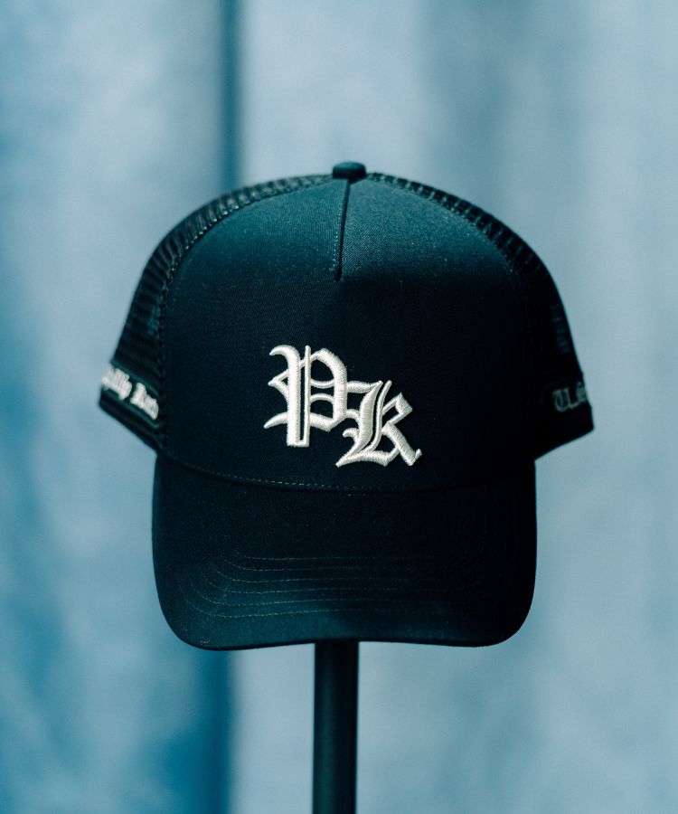Philip Karto Black PK cap with white PK logo on a blurred blue background