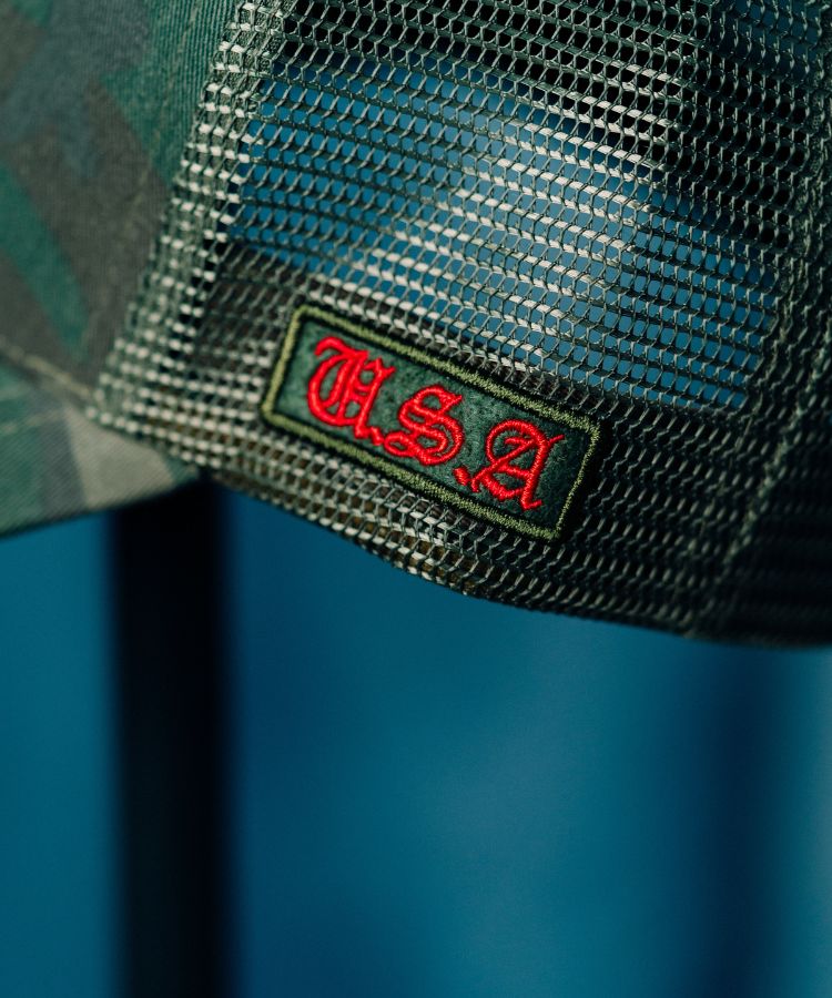 Close-up of the Camouflage PK Cap "Not For Everyone" Model by Philip Karto mesh cap with a red and black 'U.S.A' logo on a blue background
