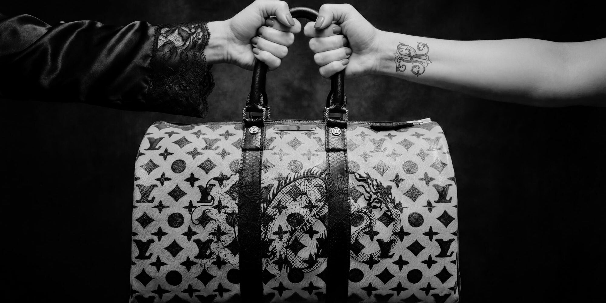 Philip Karto transformed Louis Vuitton Keepall bag in to the Black Dragon design - Image is in black and white with two hands firmily holding the bag.