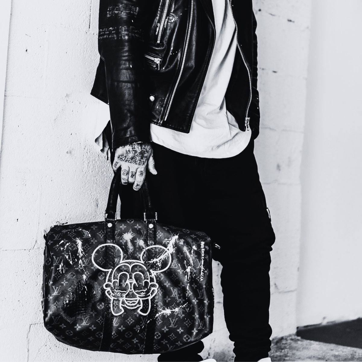 Man holding a Louis Vuitton Keepall bag with Mickey design on it. A model restoresd and revisited by Philip Karto.
